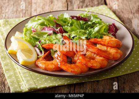 Sauté de crevettes avec du miel et de la sauce soja et de salade fraîche close-up sur une plaque sur une table horizontale. Banque D'Images