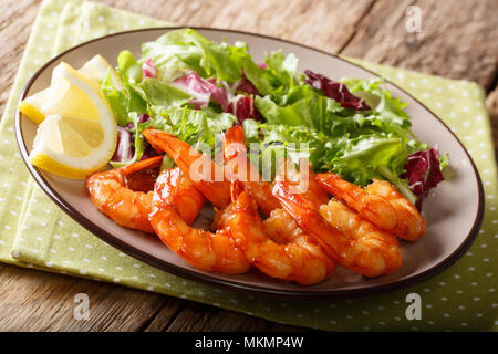 Crevettes caramélisées au miel et sauce soja et de la laitue fraîche close-up sur une plaque sur la table horizontale. Banque D'Images