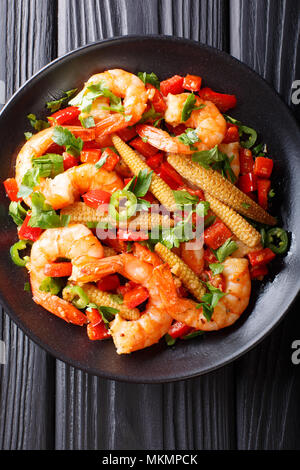 Sauté de crevettes avec du poivre, ail, herbes et d'épis de maïs gros plan sur une assiette. Haut Vertical Vue de dessus Banque D'Images