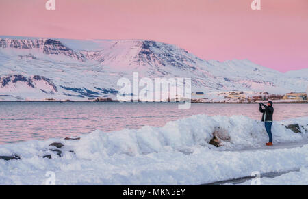 L'homme de prendre des photographies dans l'hiver au coucher du soleil, mont Esja, Reykjavik, Islande Banque D'Images