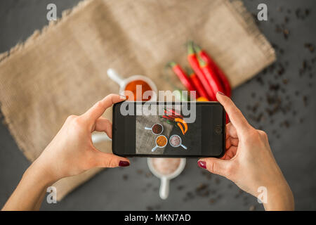 Vue de dessus d'un blogger prendre une photo d'épices dans les plats en céramique de style pour son blog culinaire avec un smartphone Banque D'Images