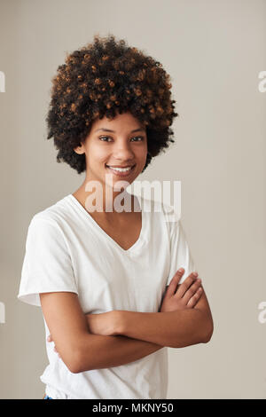 Portrait d'une jeune femme habillée en passant de l'Afrique avec un afro smiling while debout avec les bras croisés à la maison Banque D'Images
