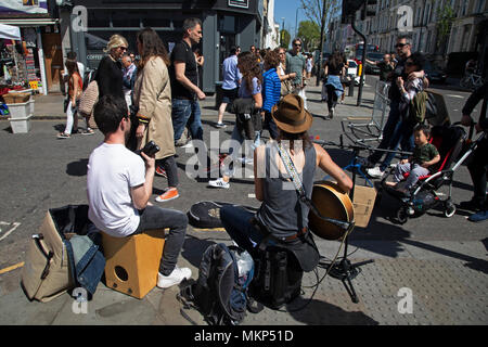 Les amuseurs publics qui joue de la guitare sur le marché de Portobello Road à Notting Hill, à l'ouest de Londres, Angleterre, Royaume-Uni. Les personnes bénéficiant d'une journée ensoleillée à traîner dans le célèbre marché de dimanche, lorsque la ligne des stands d'antiquités de la rue. Portobello Market est le plus grand marché d'antiquités avec plus de 1 000 distributeurs de vendre tout type de meubles anciens et de collection. Visiteurs viennent du monde entier pour marcher le long d'une des rues les plus appréciés de Londres. Banque D'Images