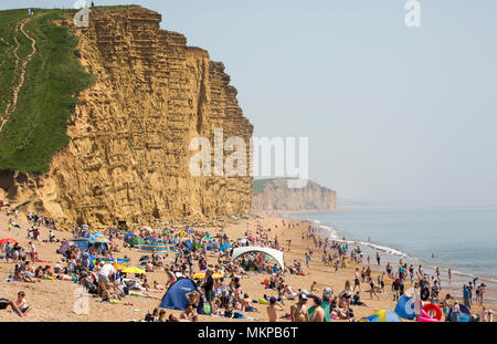 Les visiteurs sur la plage d'East Cliff à côté de West Bay et son port, profiter du soleil et nager sur les sex 7 mai Jour férié en 2018. Banque D'Images