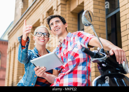 Couple sur la planification de voyage ville leur Vespa tour using tablet PC Banque D'Images