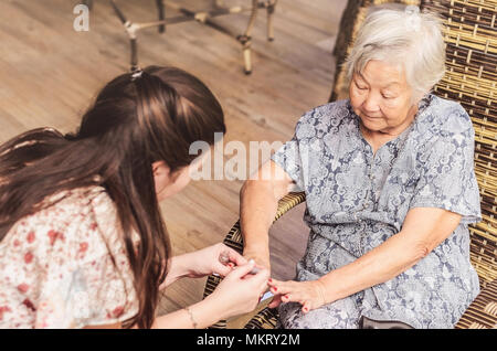 Dame ayant ses ongles peints par une plus jeune fille. Banque D'Images