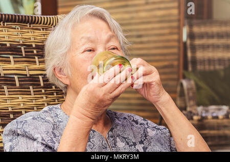 Vieille dame assis confortablement à la maison boire une tasse de café. Banque D'Images