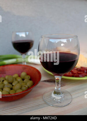 Dégustation de vins - deux verres de vin rouge avec des tranches de saucisson, fromage, olives et oignons Banque D'Images