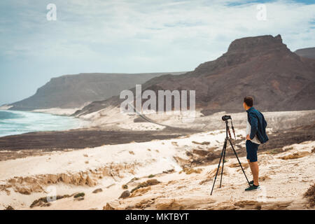 Photographe avec appareil photo en admettant désert paysage unique de dunes de sable des falaises volcaniques sur la côte atlantique. Baia das Gatas, Calhau, près de l'île de Sao Vicente Cap Vert Banque D'Images