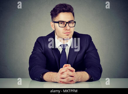 Portrait of handsome serious businessman sitting at table in office looking at camera. Banque D'Images