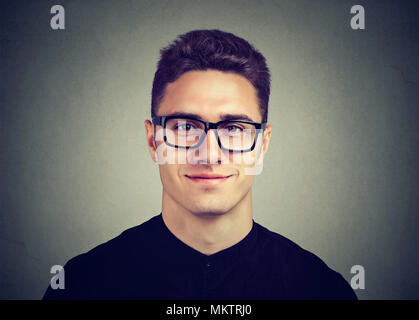 Smiling attractive l'Homme à lunettes avec une coiffure moderne posant contre un arrière-plan gris foncé Banque D'Images