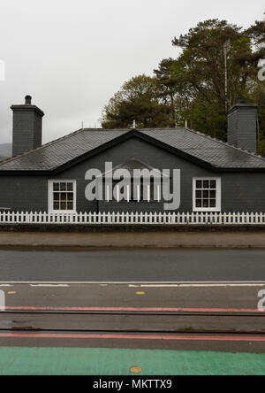 Maison en ardoise avec deux cheminées et piquet de bois blanc Clôture, lignes de chemin de fer et route en premier plan à Porthmadog pays de galles du nord royaume-uni Banque D'Images