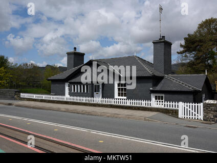 Maison en ardoise avec deux cheminées et piquet de bois blanc Clôture, lignes de chemin de fer et route en premier plan à Porthmadog pays de galles du nord royaume-uni Banque D'Images