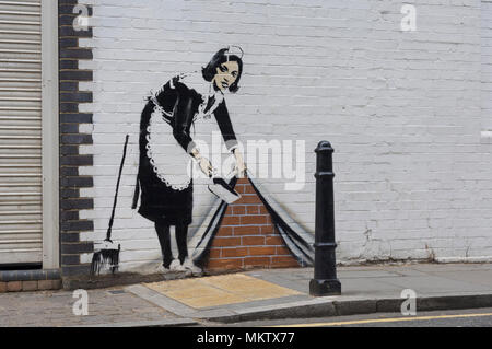 Servante de Bansky balayer sous le tapis, peint sur le mur de la galerie White Cube. Rufus Street, London, N1, en Grande-Bretagne. Banque D'Images
