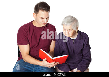Beau jeune homme, la lecture d'un roman avec des personnes âgées handicapées grand-mère sur fond isolé Banque D'Images