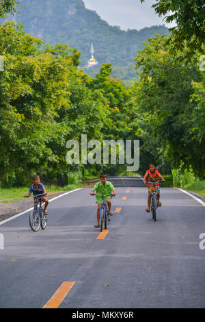 Lopburi, Thaïlande - 21 juillet 2013 : Trois garçons avec des couleurs de shirts riding bicycles on rural road à Lopburi, Thaïlande Banque D'Images