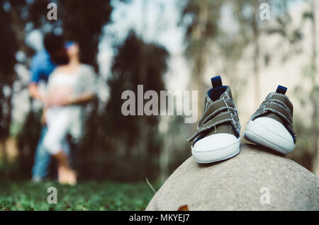 Chaussures bébé sur une pierre, avec l'arrière-plan flou parents Banque D'Images