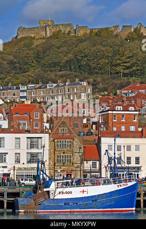 Le Château de Scarborough et remparts s'asseoir au-dessus d'un bateau de pêche amarré au port de la ville, ci-dessous. Banque D'Images