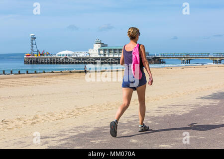 Bournemouth, Dorset, UK. Le 9 mai 2018. Météo France : le soleil brille toujours ! Un autre ensoleillé chaud pour commencer la journée, en tant que visiteurs, chef de la plage avant le temps change. Femme se promenant le long du front de mer. Credit : Carolyn Jenkins/Alamy Live News Banque D'Images