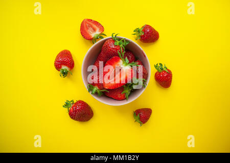 De belles fraises juteuses frais dans un bol rose sur fond jaune vif. Banque D'Images