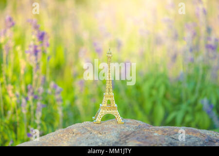 Image lumineuse d'une tour Eiffel miniature avec des champs de lavande en arrière-plan à jour . la culture française . Banque D'Images