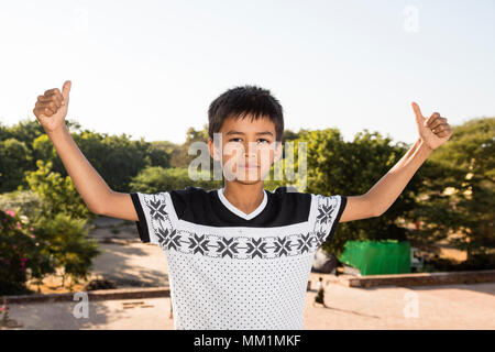 Bagan, Myanmar, 29 Décembre 2017 : Ultracool garçon posant fièrement devant la caméra et pouces vers le haut avec les deux mains à Bagan, Myanmar Banque D'Images