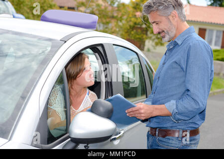 Pilote de l'apprenant à la fenêtre de la voiture de parler à l'instructeur Banque D'Images