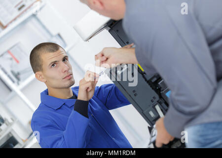 Libre tourné jeune mâle réparation technicien photocopieur numérique machine Banque D'Images