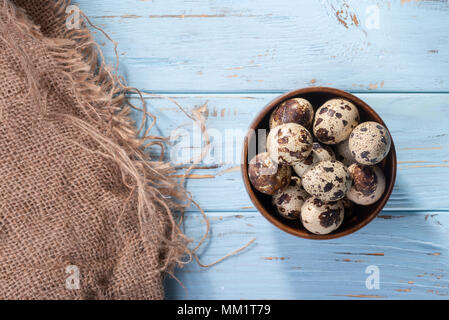 Cailles oeufs dans une assiette sur un tableau bleu avec de la toile de jute Banque D'Images