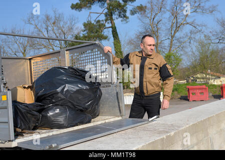 Travail heureux homme debout près de poubelle sur street Banque D'Images