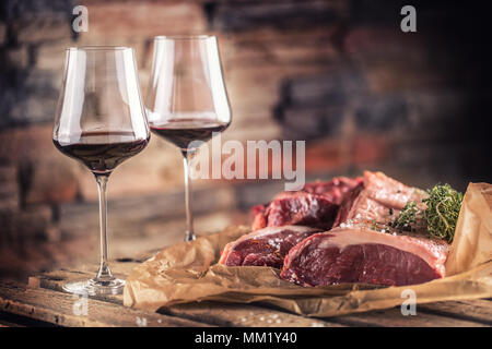 Deux tasses avec le vin rouge et le boeuf cru steak sur table en bois. Banque D'Images