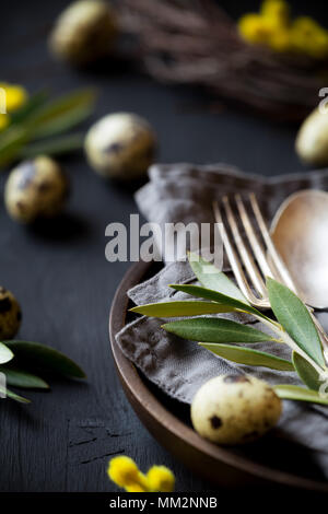 Table de Pâques avec une plaque, l'argenterie vintage gris sur une serviette décorée de branches d'oliviers et des oeufs de cailles sur table en bois noir. Les PED Banque D'Images