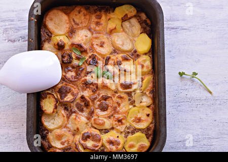 La moussaka, un plat à base de pommes de terre dans les cuisines des Balkans et de la Méditerranée/ moussaka grecque traditionnelle avec le boeuf haché et les pommes de terre sur une table en bois Banque D'Images