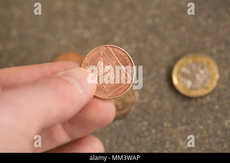 Pose photo de ramassage d'une pièce deux pence monnaie avec d'autres derrière. UK Banque D'Images