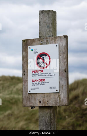 Inscrivez-avertissement ne pas creuser ou s'enfouissent dans les dunes de sable en raison du danger d'effondrement posté par Ressources naturelles du pays de Galles sur Harlech beach dans le Nord du Pays de Galles Banque D'Images