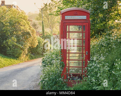 La boîte de téléphone rouge sur un chemin de campagne au printemps Banque D'Images