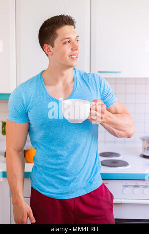 Jeune homme de boire du café dans la cuisine format portrait matin smiling Banque D'Images