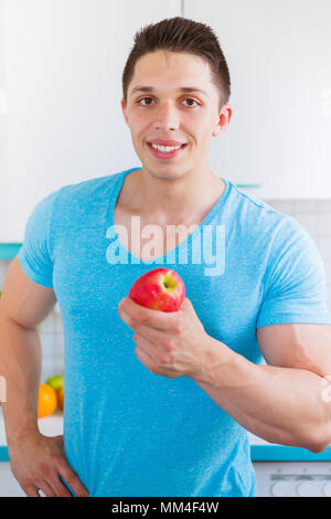 La saine alimentation jeune homme manger pomme fruit dans la cuisine vertical format portrait Banque D'Images