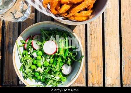 Dîner sain avec Salade de brocoli grillés, petits pois, radis, menthe fraîche et fromage de chèvre émietté et frites de patates douces cuites au four Banque D'Images