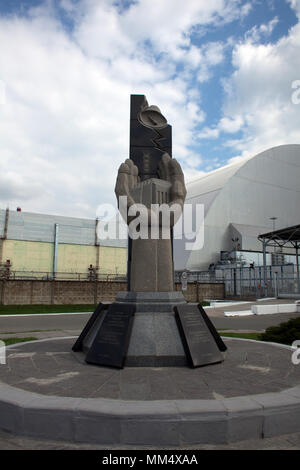Mémorial pour les liquidateurs à Tchernobyl avec nouveau confinement de sécurité (NSC) nouveau sarcophage sur réacteur endommagé 4 dans l'arrière-plan Banque D'Images
