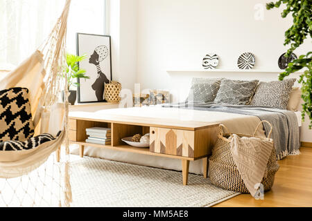 Armoire rustique en bois en face du lit avec des coussins dans la chambre intérieur avec poster Banque D'Images