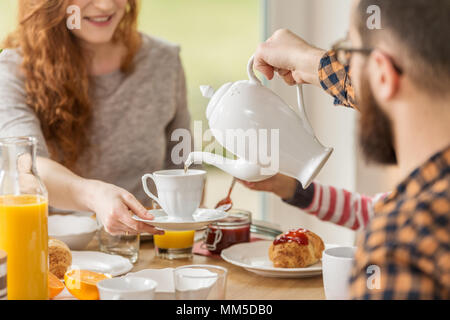 Plateau en versant mari épouse's cup lors du petit déjeuner à la maison Banque D'Images