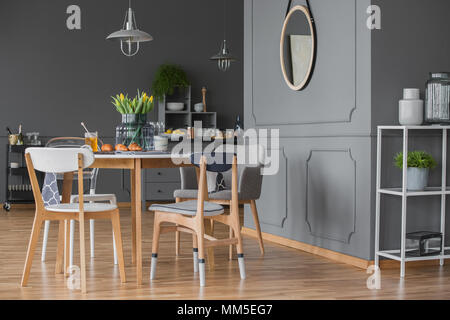 Vue de côté cuisine intérieur gris avec une table à manger, chaises, miroir, et moulure murale Banque D'Images