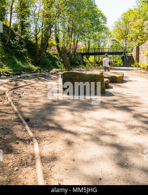 Sentier sur le côté de la rivière à holmfirth, rochers au premier plan, les femmes à la recherche de l'appareil photo, pont sur la rivière et le canard colvert Banque D'Images