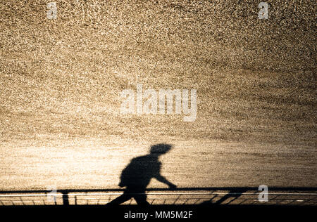 Flou flou artistique ombre silhouette d'un homme marchant sur la route luisante sur le coucher du soleil Banque D'Images