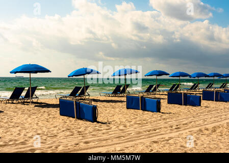 Blue lounge chaises et parasols bleus une ligne de plage de la Floride sous ciel bleu. Banque D'Images