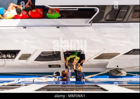 Passagers et produits sont transférés d'un bateau de plongée à un autre milieu de l'océan au-dessus de la Grande Barrière de Corail, Queensland, Australie. Banque D'Images