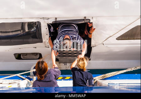 Passagers et produits sont transférés d'un bateau de plongée à un autre milieu de l'océan au-dessus de la Grande Barrière de Corail, Queensland, Australie. Banque D'Images