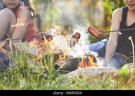 Les enfants bénéficient de camp. Les filles (famille) faire griller les saucisses sur le jardin. Banque D'Images