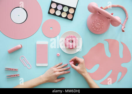 Photo recadrée d'une jeune fille peinture ses ongles sur un tableau bleu avec points rose Banque D'Images